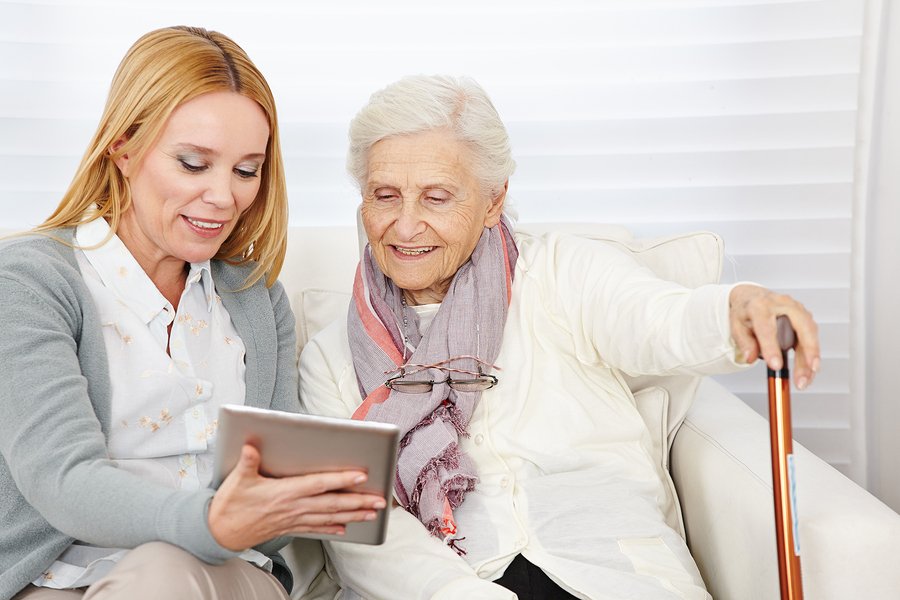 Woman giving senior woman introduction to internet with a tablet